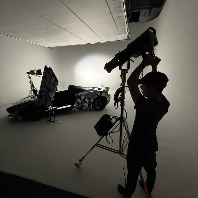 No horizon line. The curved white cyc wall and floor in our studio run in one sweep behind the car, so the shape comes from the fixtures the crew places. Here one sits on a roller stand while a second rakes across the wrap.

#fivesixstudio #cyclorama #carphotography #studiolighting #lasvegasstudio